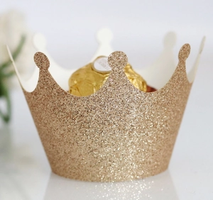 Detail of glitter gold crown cupcake wrapper with shiny metallic finish for party decor