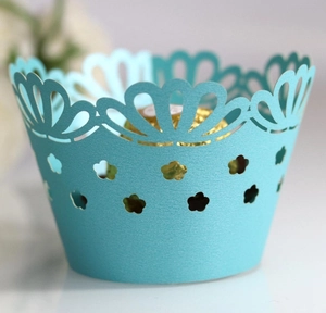 Macro shot of light blue laser-cut cupcake wrappers with elegant petal edge and plum patterns