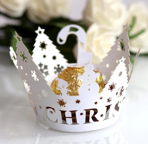 Macro shot of white laser-cut Christmas tree cupcake liners with festive snowman hollow patterns