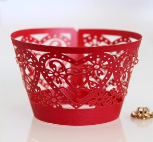 Close-up of laser-cut red cupcake wrappers with intricate heart and floral hollow patterns