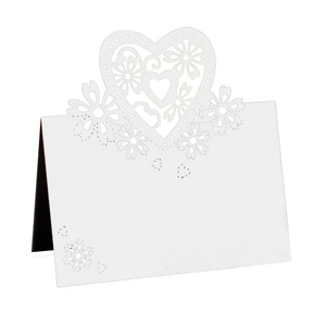 Dettaglio di cuori e fiori intagliati al laser su un segnaposto bianco per matrimoni