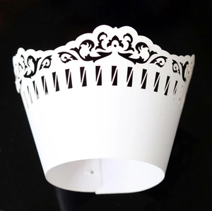 Detail of white laser-cut cupcake wrapper with elegant floral and picket fence pattern