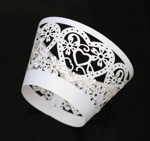 Detailed laser-cut heart and floral lace patterns on white cupcake wrappers
