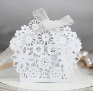 Macro shot of white laser-cut floral favor box with delicate organza ribbon bow