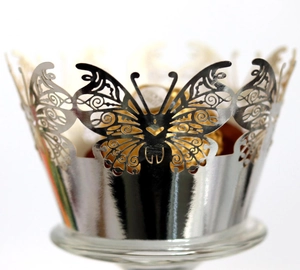 Macro detail of laser-cut silver butterfly cupcake wrapper with intricate hollow patterns