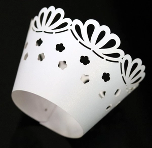 Detail of white laser-cut cupcake wrapper with floral pattern and scalloped edges