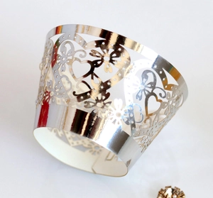 Close-up of laser-cut silver cupcake wrapper with intricate heart and floral patterns