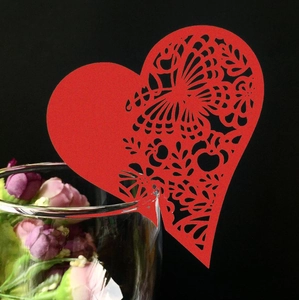Détail du marque-place coeur rouge découpé au laser avec motif papillon sur verre