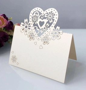 Dettaglio segnaposto avorio perlato tagliato al laser con motivi a cuore e floreali