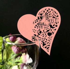 Marque-place cœur rose avec découpe laser papillon sur le rebord d'un verre