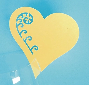 Pale yellow heart laser-cut wine glass place card with ornate hollow pattern for weddings