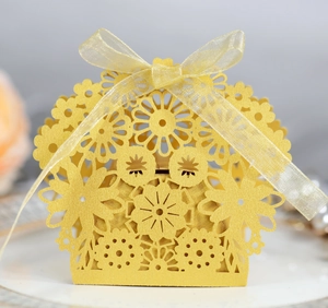 Close-up of laser-cut hollow candy gift box with elegant yellow ribbon bow and floral patterns