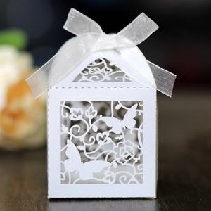 Close-up of laser-cut wedding favor box with white ribbon bow and butterfly pattern
