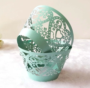 Mint green laser-cut heart pattern cupcake wrappers on white soft texture background