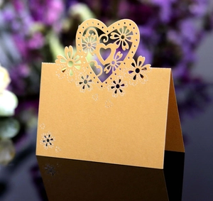 Dettaglio di cuori e fiori intagliati al laser su segnaposto in avorio perlato da tavolo