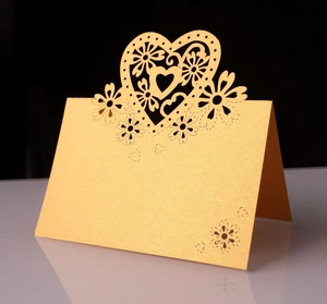 Dettaglio del segnaposto dorato tagliato al laser con motivi floreali e cuore per nozze