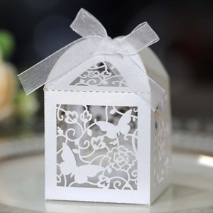Close-up of laser-cut white butterfly wedding favor box with delicate organza ribbon bow