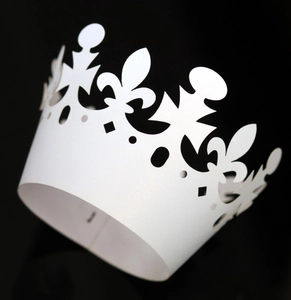Macro shot of white laser-cut cake lace wrapper with intricate fleur-de-lis pattern