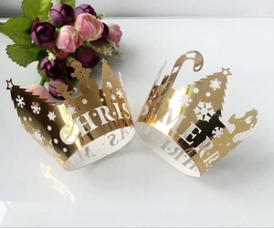 Detailed view of laser-cut gold Christmas cupcake wrappers with tree and snowflake patterns