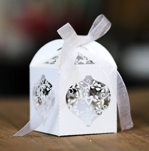Detailed laser-cut pattern on a white wedding favor box with a delicate ribbon bow