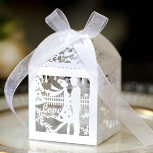 Macro shot of laser-cut white wedding candy box featuring a romantic couple silhouette
