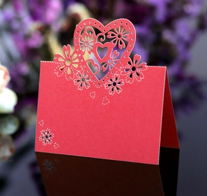 Dettaglio del segnaposto rosso a cuore tagliato al laser con motivi floreali su base lucida