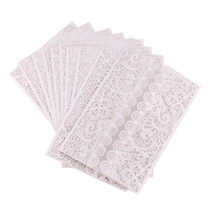 Detailed view of intricate laser-cut floral lace patterns on white paper invitations