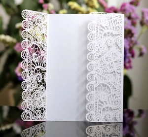 Detailed laser-cut lace floral pattern on elegant white wedding invitation cover