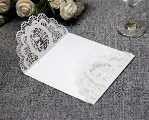 Dettaglio dell'invito di nozze bianco tagliato al laser con pizzo e uccellini eleganti