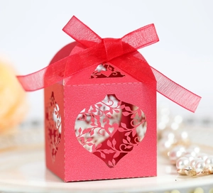Close-up of red laser-cut heart pattern gift box with ribbon and elegant pearl decor