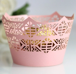 Close-up of pink laser-cut cupcake wrappers with geometric patterns and crown edges