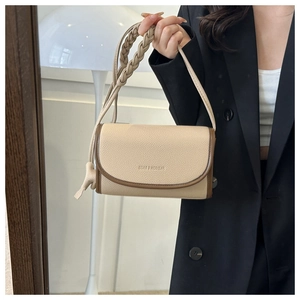 Detail of beige small square crossbody bag with brown trim and woven shoulder strap