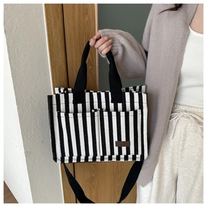 Detail view of the striped canvas tote bag showing side pockets and fashion leather label