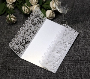 Macro view of white laser-cut lace invitation card with intricate floral patterns