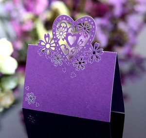 Dettaglio segnaposto viola tagliato al laser con cuori e motivi floreali per matrimoni