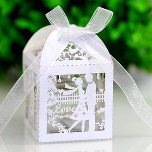 Macro shot of laser-cut white favor box featuring couple silhouette and Love text