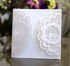 Detailed laser-cut white wedding invitation with elegant birdcage and lace pattern