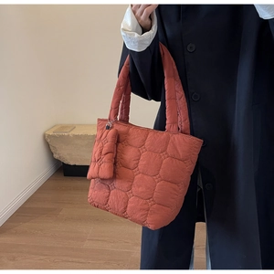 Détail du sac cabas matelassé orange caramel montrant la texture et la chaîne argentée