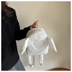 Detailed view of white faux fur heart backpack featuring adjustable straps and soft texture