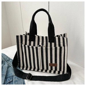 Detailed shot of black and white striped canvas tote with brown leather fashion label