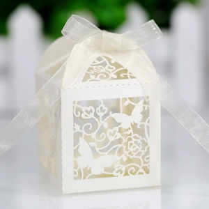 Close-up of laser-cut white wedding favor box with intricate butterfly and floral patterns