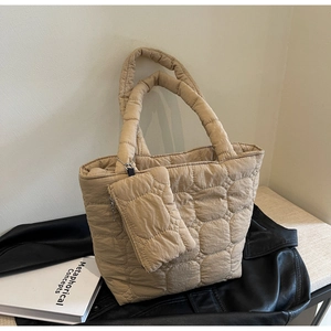 Détail du sac cabas matelassé beige avec sa pochette zippée assortie sur fond minimaliste