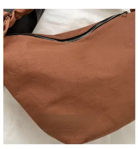 Close-up of brown canvas crescent bag with black zipper detail and textured surface