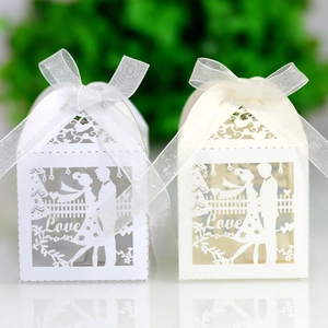 Detail of laser-cut wedding favor boxes with Love text and silk ribbon in macro view