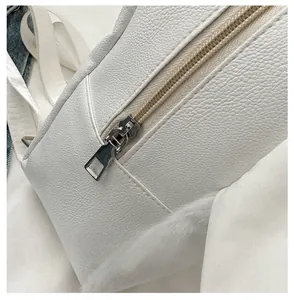 Detail of silver smooth zipper and white lychee pattern leather on a crossbody bag