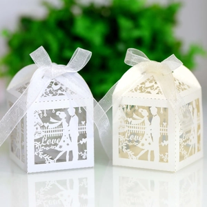 Macro detail of laser-cut wedding favor boxes with love lettering and satin ribbons