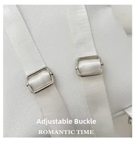 Detail of adjustable metal buckles on white litchi leather bag strap with romantic text