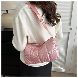 Detail of pink quilted down fabric crossbody bag with metallic finish and wide strap