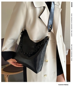 Detail of black pleated tote bag featuring large chain link and wide shoulder strap