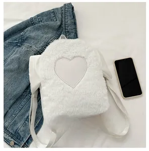 Detail of white faux fur mini backpack with heart patch next to a smartphone